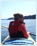 A woman in red jacket sitting on a kayak.